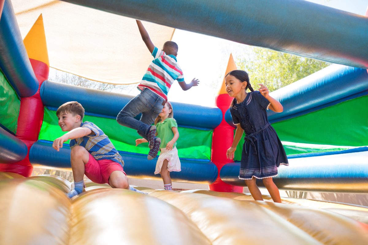 Children jumping and playing inside a colorful inflatable bounce house during a party event outdoors